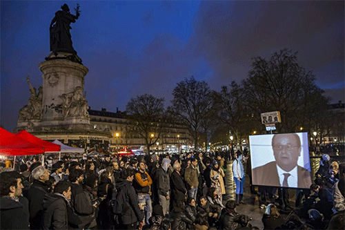 Integrantes del movimiento "La Nuit Debout" observan una intervención de Francois Hollande en París